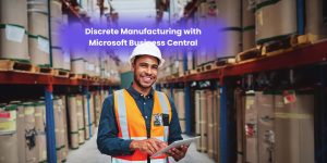A smiling warehouse worker in a safety vest holds a tablet while standing in an industrial storage area filled with rolls of material.