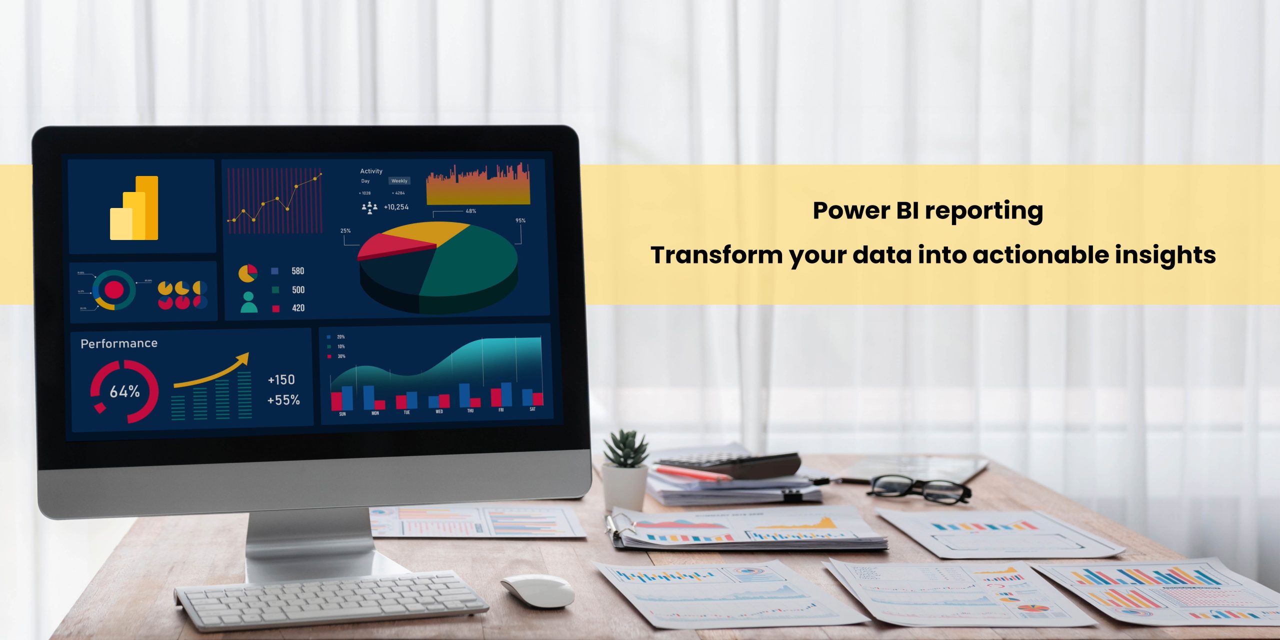 A computer monitor displaying a Power BI dashboard with various colorful charts and graphs, set on a wooden desk alongside papers and a pair of glasses.